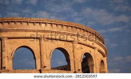Ancient stone arch structure captured under a clear blue sky with warm light and curved arches