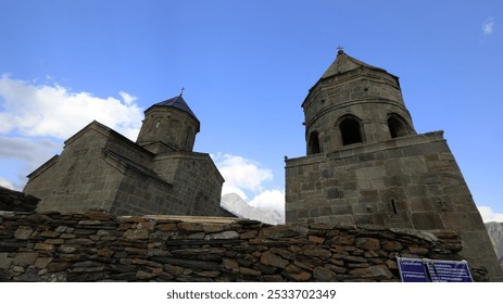 Ancient stone church towers against a clear blue sky in Kazbegi, Georgia, showcasing historical architecture. - Powered by Shutterstock