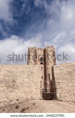 ancient stone fortress with a gated entrance stands under a cloudy sky, exuding historical and architectural significance