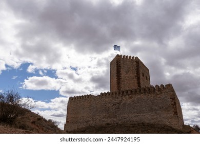 ancient stone fortress overlooking a modern town against rolling hills and a cloudy sky - Powered by Shutterstock