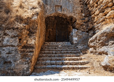 An ancient stone staircase leads to a gated archway at the historic Castle of Kalamata, showcasing medieval architecture and history. - Powered by Shutterstock