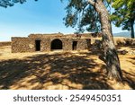 An ancient stone structure within the Kalamata Castle grounds, showcasing medieval architecture surrounded by trees and open space.