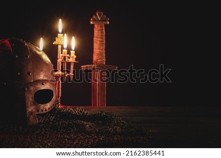 Ancient sword, armor and helm on the wooden table background. Front view.