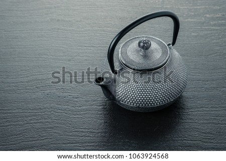 An ancient teapot for brewing green tea on a gray background