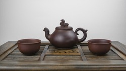 An Ancient Teapot And Two Clay Bowls On A Wooden Surface With A White Background