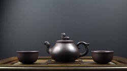 An Ancient Teapot And Two Clay Bowls On A Wooden Surface With A Grey Background