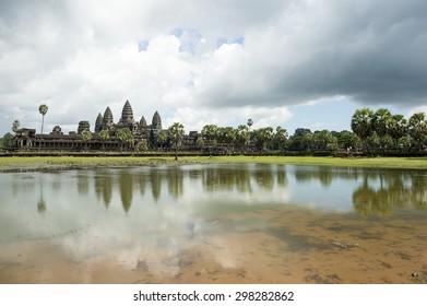 Ancient temple complex of Angkor Wat reflecting in still water under dramatic sky - Powered by Shutterstock