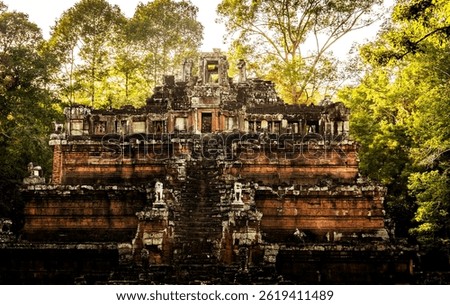 An ancient temple structure surrounded by lush green trees, showcasing intricate stone carvings and a grand staircase leading to the entrance. The sunlight filters through the foliage, creating a sere