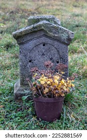 A ancient tombstone with withered flowers in a flowerpot. - Shutterstock ID 2252881569