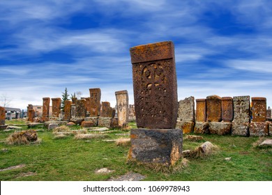 Ancient Tombstones Known As Khachkars Covered With Moss And Lichen In The Historical Cemetery Of Noratus In Armenia, Near The Lake Sevan Under The Beautiful Blue Sky. 10th Century