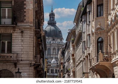 Ancient towers of St. Stephen's Basilica, a Roman Catholic Cathedral among historical buildings in the old town of Budapest, Hungary, Europe. The streetscape of downtown neighborhood houses.