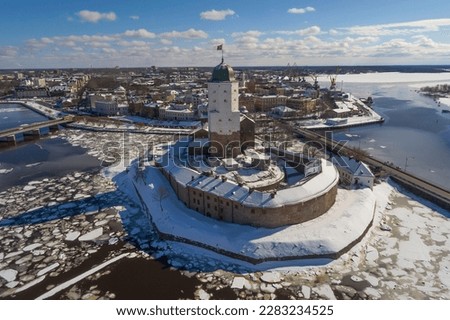 The ancient Vyborg castle against the background of the cityscape on a sunny March day (aerial photography). Vyborg, Leningrad region. Russia