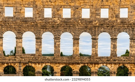 ancient wall with arches and windows of historical building, ancient architecture outdoor , roman arena in Pula , Croatia