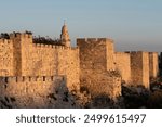 The ancient walls of the Old City of Jerusalem bathed in a golden glow at sunset in Israel. 