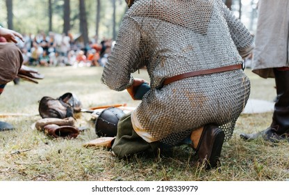 An Ancient Warrior In Chain Mail Sitting On The Grass, Close-up, Rear View, Low Angle View.