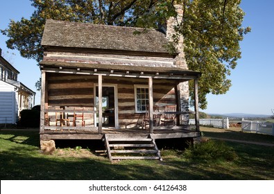 Ancient wooden cabin and porch under large fall tree