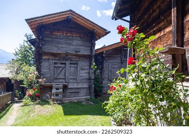 Ancient wooden traditional Swiss racecard granaries and chalets on stone piles and red roses in front in an old village in Switzerland - Powered by Shutterstock