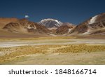 The Andes mountain range. Panorama view of the yellow meadow, the brown mountains, golden valley and Volcano Incahuasi, under a deep blue sky.