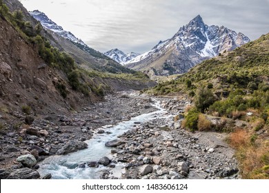 Andes valleys inside central Chile at Cajon del Maipo, an amazing rugged landscape with steep mountains and an awe scenery with the river in the valley surrounded by forest and snowcapped mountains
