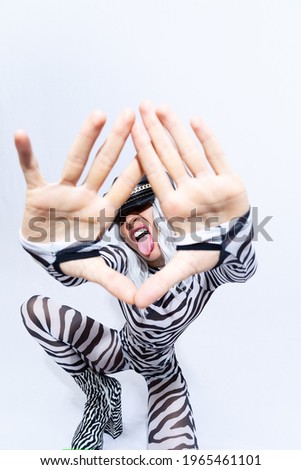 androgenic blonde model in freak stylish zebra print clothes and leather trendy black cap  selfies in a white studio. Clubbing party style