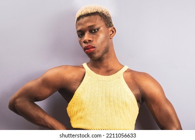 An Androgynous Black Man Posing On A Purple Studio Background In Makeup.