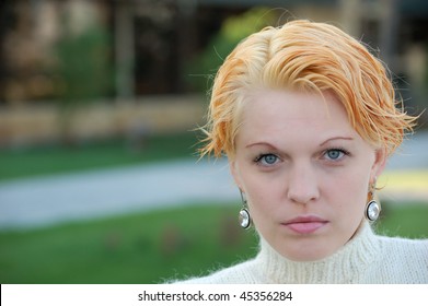 Androgynous Look Pretty Blonde Woman With Queer Haircut Portrait Headshot. A Lot Of Copyspace On Blurred Background.