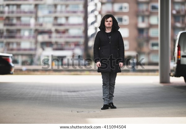 Androgynous man standing on\
parking lot