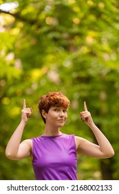 Androgynous Woman Pointing Up In A Park