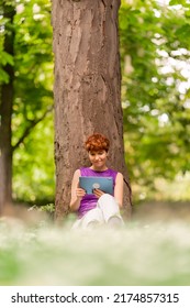 Androgynous Woman Watching Video In A Park