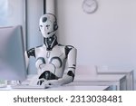 Android AI robot sitting at the desk and working in the office: artificial intelligence, business and automation concept