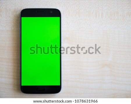 Android Smartphone with green screen vertically oriented shot top down on wood table