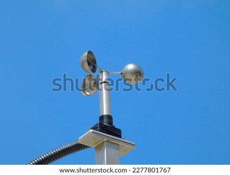 anemometer wind speed indicator measuring device fixed to aluminum bracket on tube post. meteorological device. abstract low angle view. spoon shaped semi sphere blades. clear blue summer sky
