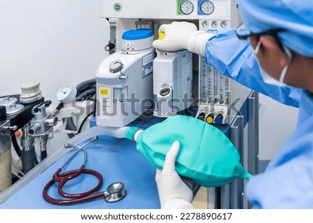 Anesthesiologist or doctor in blue gown working with anesthetic machine inside operating room in hospital.Right hand control machine with ambu bag.Medical device for surgery.Gas exchange control. ストックフォト © 