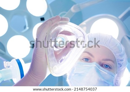 Anesthesiologist holding oxygen mask for induction in operating room Imagine de stoc © 