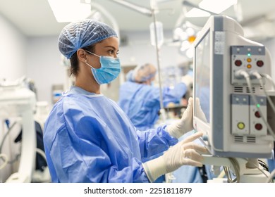 Anesthesiologist keeping track of vital functions of the body during cardiac surgery. Surgeon looking at medical monitor during surgery. Doctor checking monitor for patient health status.