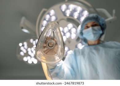 Anesthesiologist puts an oxygen mask on the patient.  Preparing for surgery. The doctor administers inhalation anesthesia using an anesthesia machine before intubation. Emergency and first aid concept - Powered by Shutterstock