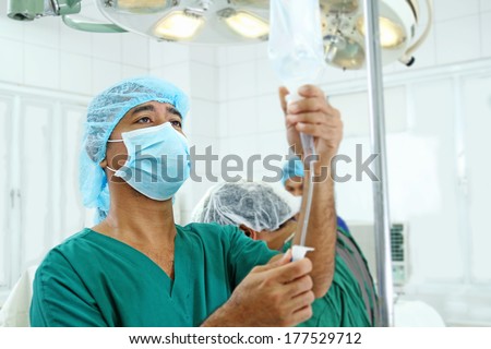 Anesthesiologist regulating an iv drip inside the operating room.