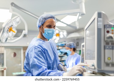 Anesthetist Working In Operating Theatre Wearing Protecive Gear checking monitors while sedating patient before surgical procedure in hospital - Powered by Shutterstock