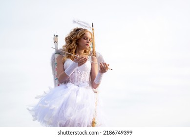 Angel Child Girl With Curly Blonde Hair. Concept Of Innocent Child. Lovely Girl Cupid With Bow And Arrow Is Ready To Find Your Love. Cute Teen Girl