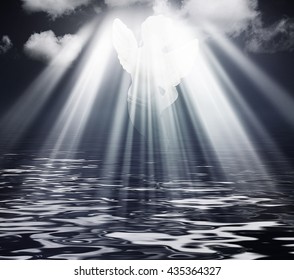 Angel in dark sky clouds with Rays of sunlight. Religion concept