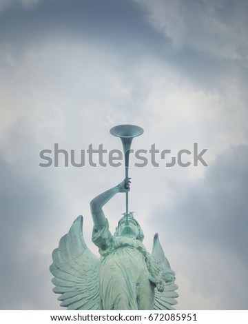 An angel figure is blowing a trumpet horn outside with a sky in the background and copyspage for a religious message.