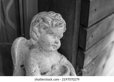 angel figurine, cement angel figure with wings, old garden figurine. black and white photography. Guardian Angel sitting on a column. beautiful ceramic figurine of an angel
