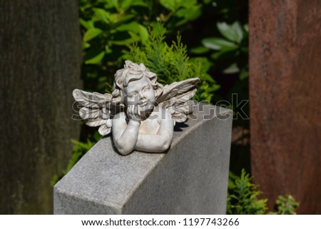 Angel figurine supports the chin with his hand and lies on a marble stone
