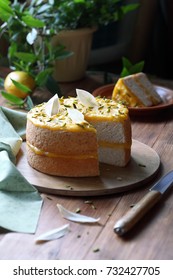 Angel Food Cake With Lemon Curd Decorated With Pistachios And White Chocolate Leaves, On Wooden Board, On Wooden Table.