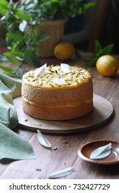 Angel Food Cake With Lemon Curd Decorated With Pistachios And White Chocolate Leaves, On Wooden Board, On Wooden Table.