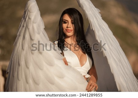 an angel girl with big white wings stands on a mountain at dawn. Early morning, angel on the mountain. The white angel. Sunrise.