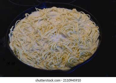 Angel Hair Pasta Simmering In White Sauce On Stove
