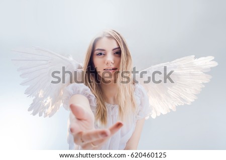 An angel from heaven gives you a hand. Young, wonderful blonde girl in the image of an angel with white wings.