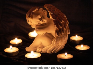 Angel Sculpture Surrounded By Burning Candles; Grief And Loss Memory Of The Deaths Concept