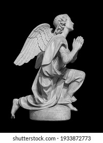 Angel statue isolated on black background. White stone sculpture of praying cherub